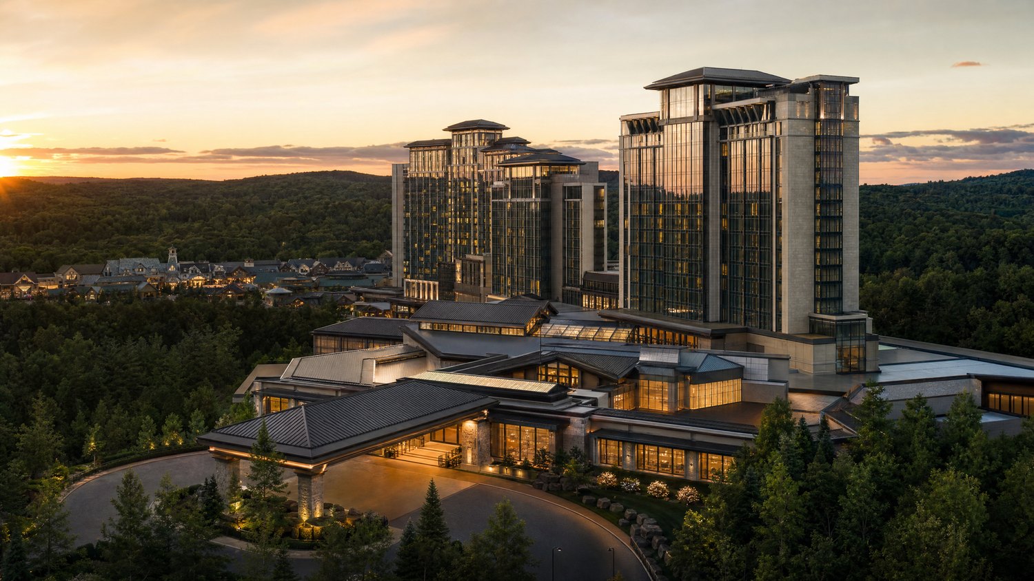 A multi-tower resort rising above dense Connecticut woodland at sunset.